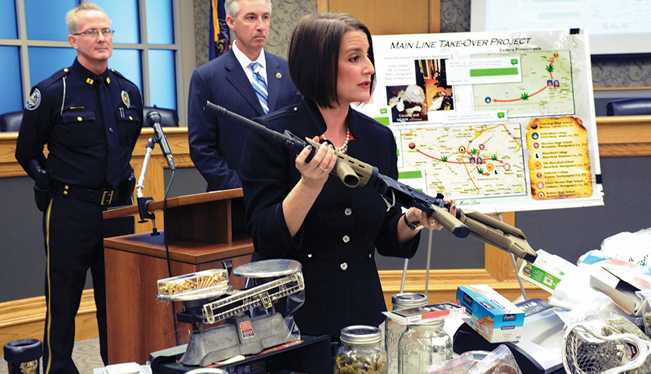 Montco D.A. Risa Ferman with an AR-15 rifle and drugs seized by the police.  / Associated Press