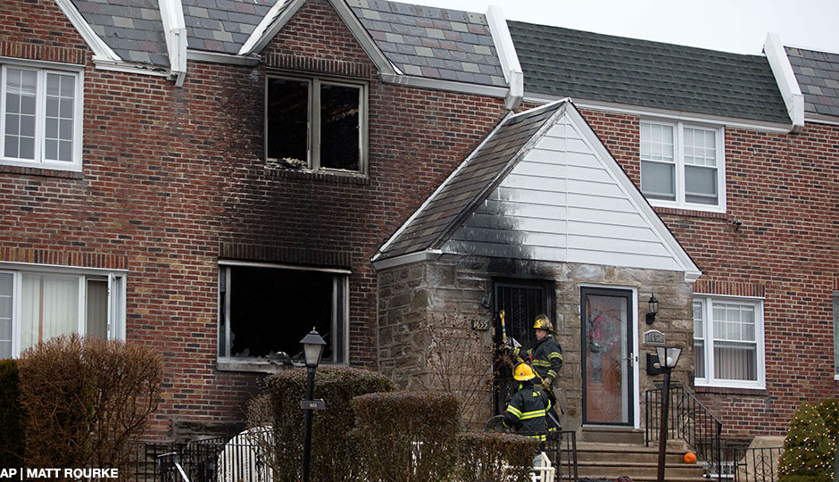 Firefighters enter a burned-out home in the aftermath of a fatal fire Tuesday, Dec. 9, 2014, in Philadelphia. A firefighter was trapped in the basement of the burning row home early Tuesday, becoming the first female member of the Philadelphia Fire Department to die in the line of duty, officials said. The 11-year veteran was part of the first company deployed to a fire in the basement of the home in the city's West Oak Lane neighborhood at about 3 a.m. Tuesday, fire commissioner Derrick Sawyer said.