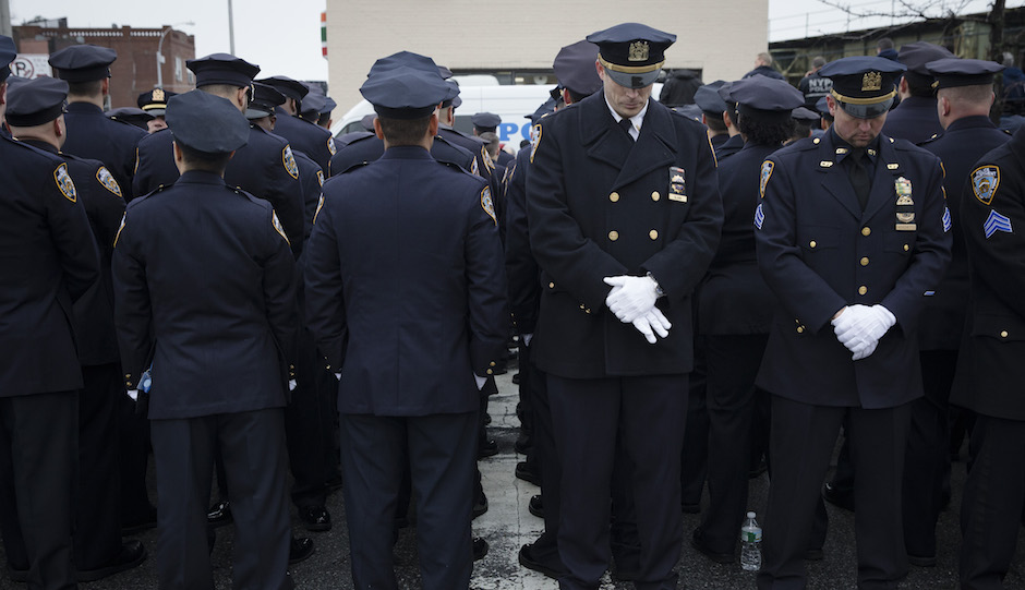 Some police officers, left, turn their backs in a sign of disrespect as Mayor Bill de Blasio speaks as others, at right front line, stand at attention, during the funeral of New York Police Department Officer Wenjian Liu at Aievoli Funeral Home, Sunday, Jan. 4, 2015, in the Brooklyn borough of New York. Liu and his partner, officer Rafael Ramos, were killed Dec. 20 as they sat in their patrol car on a Brooklyn street. The shooter, Ismaaiyl Brinsley, later killed himself. (AP Photo/John Minchillo)