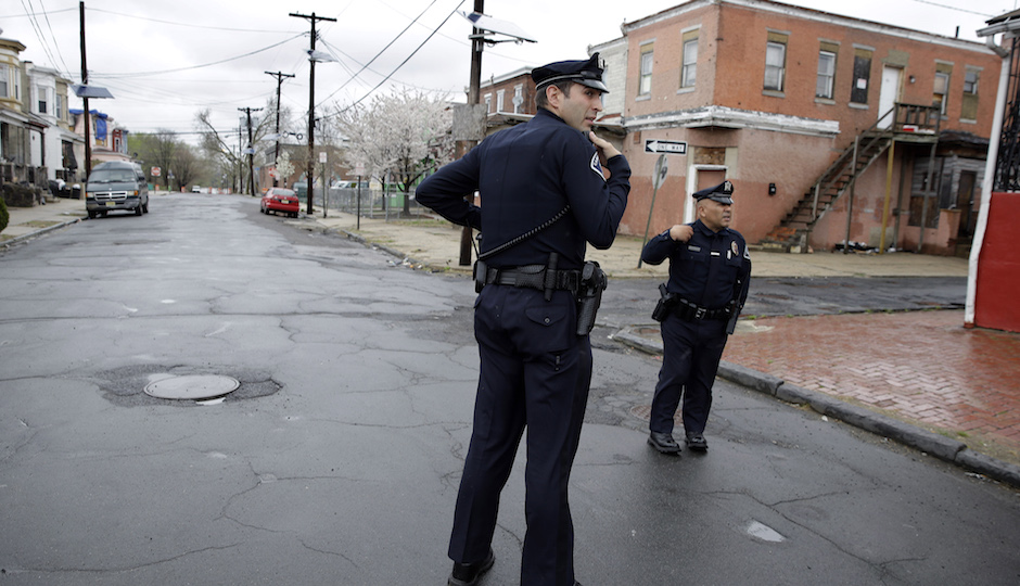 In this April 15, 2014 file photo, Camden County Metro police officers Lucas Murray, left, and Daniel Torres react to what they thought was a gunshot, but turned out to be a car backfiring, as they patrol a neighborhood in Camden, N.J.  The crime rate always fluctuates, but recent improvements in Camden are getting major attention because of the circumstances. The city’s old police department was dissolved in 2013 and replaced with a force run by the county government. With lower costs per officer, the new force is bigger, allowing for more beat-driven police work and preventative policing. (AP Photo/Mel Evans, File)