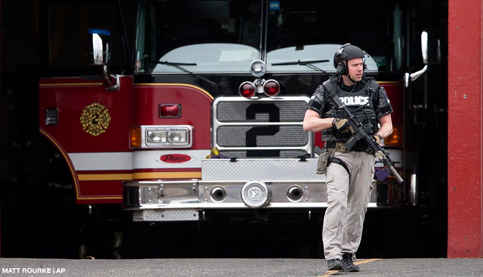 An officer walks out of the LaMott Fire Company after police escorted a man away, Tuesday, March 31, 2015, in Elkins Park, Pa. Authorities say a former volunteer firefighter held four firefighters hostage at the Philadelphia-area firehouse before surrendering to police. No injuries were reported.
