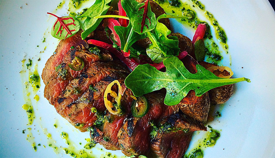 Grilled steak with a bright green chimichurri, ash-roasted fingerling potatoes, and a cippolini onion cream