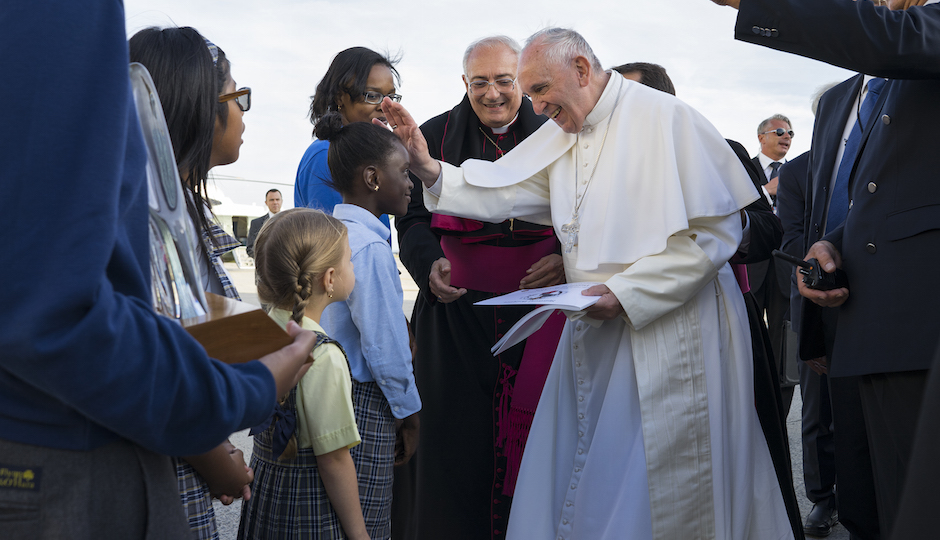 Pope Francis reaches out to 5th grader Omodele Ojo of the Brooklyn borough of New York as he is greeted by children upon arrival at John F. Kennedy International Airport Thursday, Sept. 24, 2015, in New York. The pope is on a five-day trip to the USA, which includes stops in Washington DC, New York and Philadelphia, after a three-day stay in Cuba. (AP Photo/Craig Ruttle, Pool)
