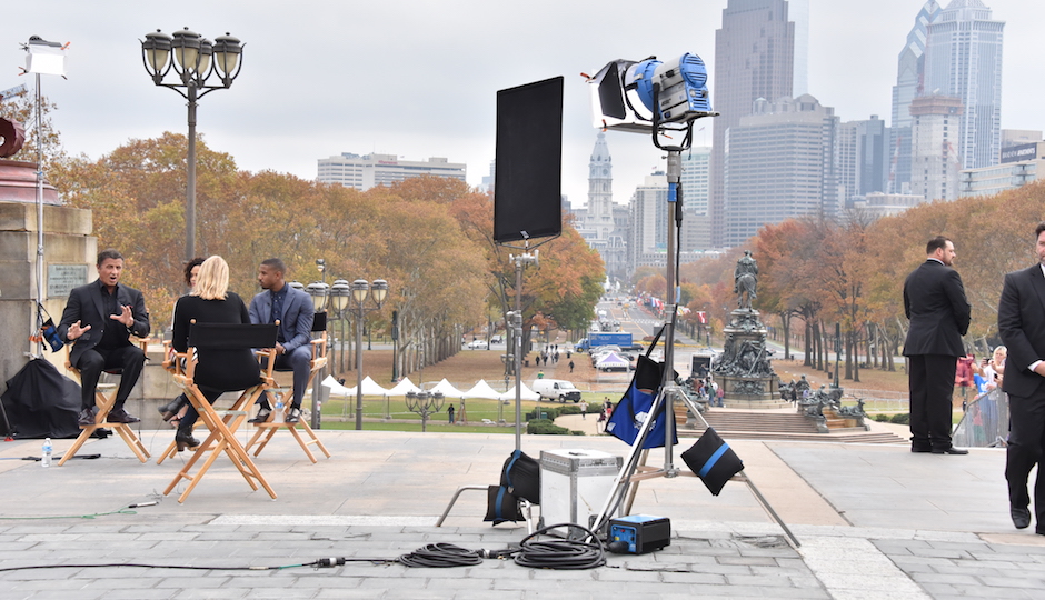 Stallone, Thompson and Jordan talk to a reporter on the "Rocky Steps" while bodyguards wait in the wings. | Photo by HughE Dillon
