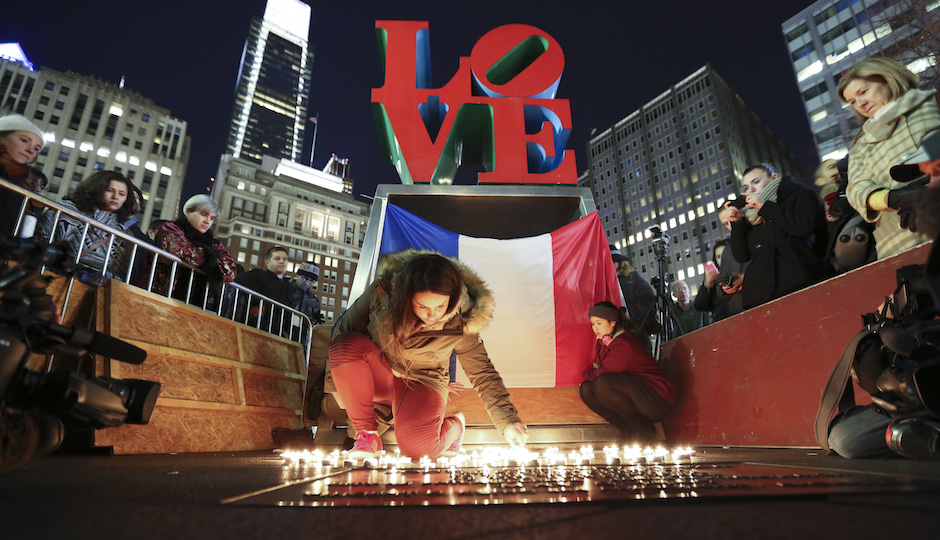 Cloe Tinchant lights candles in LOVE Park, Saturday, Nov. 14, 2015, during a candlelight vigil to remember the victims of the attacks in Paris. (AP Photo/Joseph Kaczmarek)