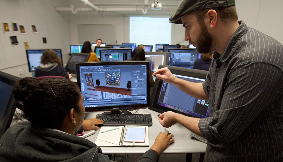 Moore's Stephen Wood with an Animation & Game Arts student on the computer.