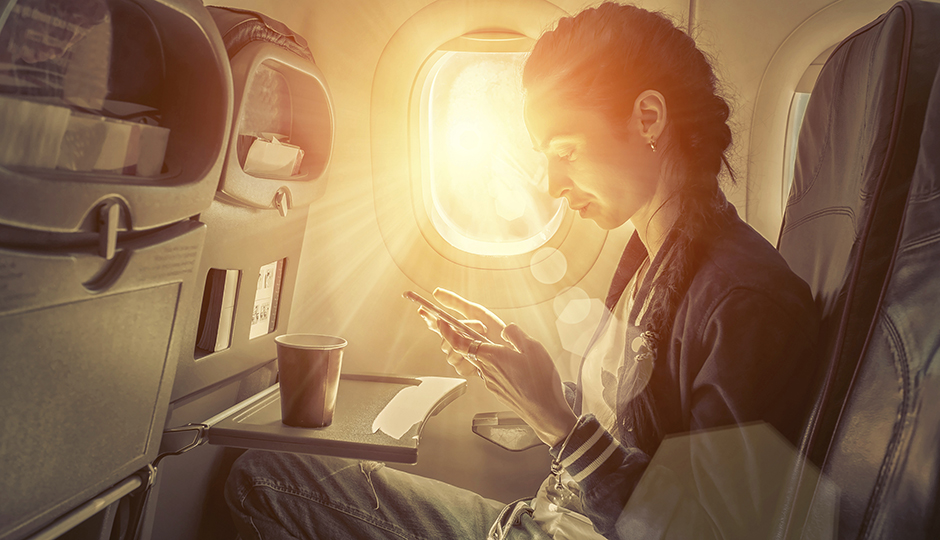 Woman sitting at airplane and looking to mobil phone.