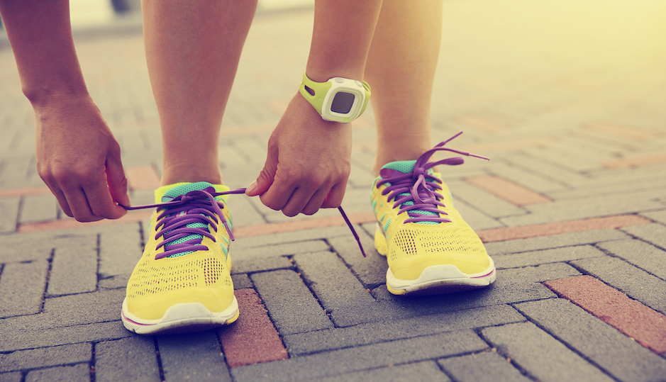 young woman runner tying shoelace at the sunrise seaside