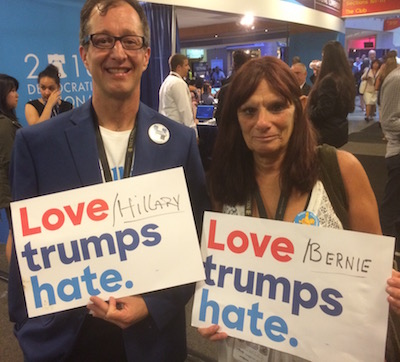 Moses Ross (left), a Clinton delegate from Portland, Ore., and Lisa Stiller, a Sanders delegate from Beaverton, Ore., offered a show of unity to conventioneers last night. Stiller loved the helpful attitude of the SEPTA personnel who helped her use the subway when she arrived on Saturday but didn't much like the two hours she had to wait for a shuttle bus on Monday afternoon as full buses passed her waiting group by.