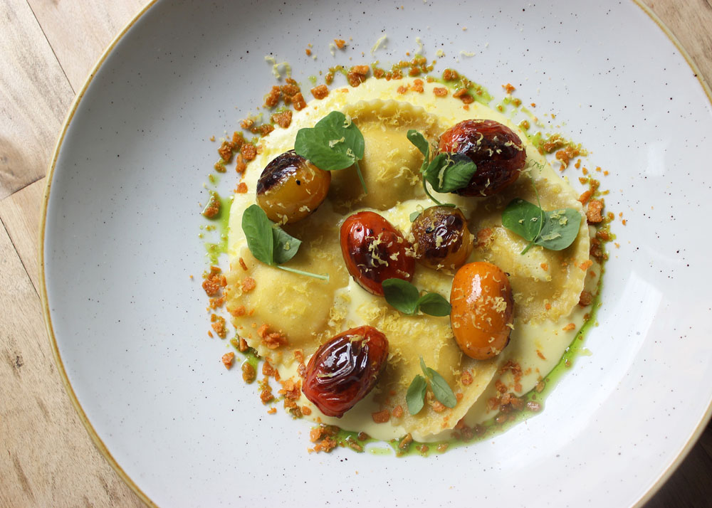 Ravioli - roasted onion ravioli, corn crema, blistered cherry tomato, cured egg yolk | Photo by Vanessa Beahn