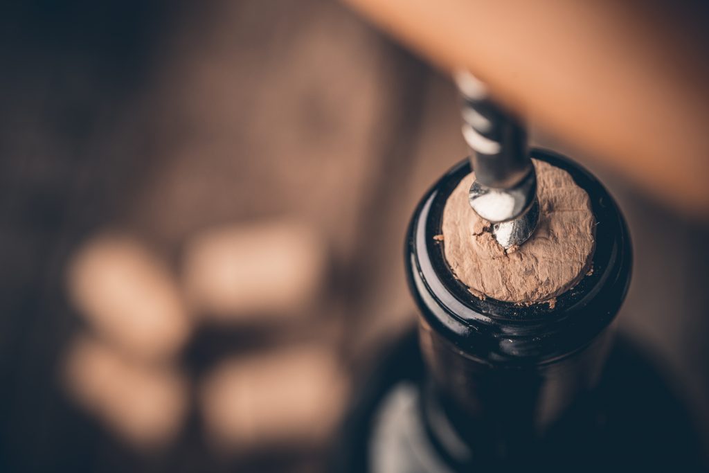 Corkscrew and bottle of wine on the board