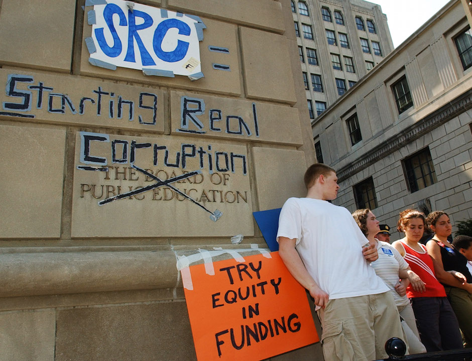 William Deadwyler, left, joins about a dozen students as they lock arms outside Philadelphia's school administration building Wednesday, April 17, 2002, forming a human chain and refusing to allow anyone inside. The Philadelphia School Reform Commission, set to announce which companies and nonprofit groups will be given control of some 75 schools in the district, decided to postpone the meeting for two hours and move it to another building several blocks away rather than make a forced entry. (AP Photo/Brad C. Bower)