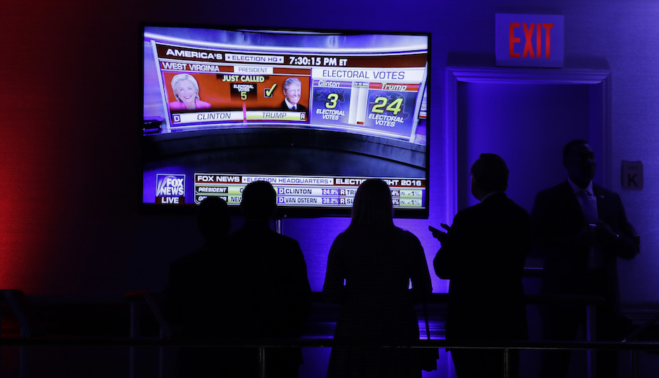 Supporters gather around the monitor to check the early election results during Republican presidential candidate Donald Trump's election night rally, Tuesday, Nov. 8, 2016, in New York. (AP Photo/John Locher)