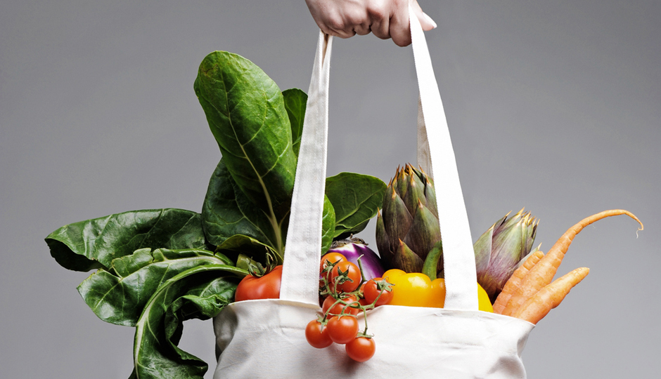 full of vegatables cotton shopping bag carried by a human hand