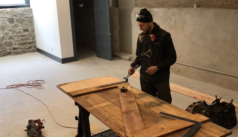 Made by hand, not beforehand: A Red Oak construction crew member works on the hinge of a custom door made from wood salvaged from the demolition of the parish house's interior. The door will lead from this home's finished basement rec room to the mechanical room. | Photos: Sandy Smith