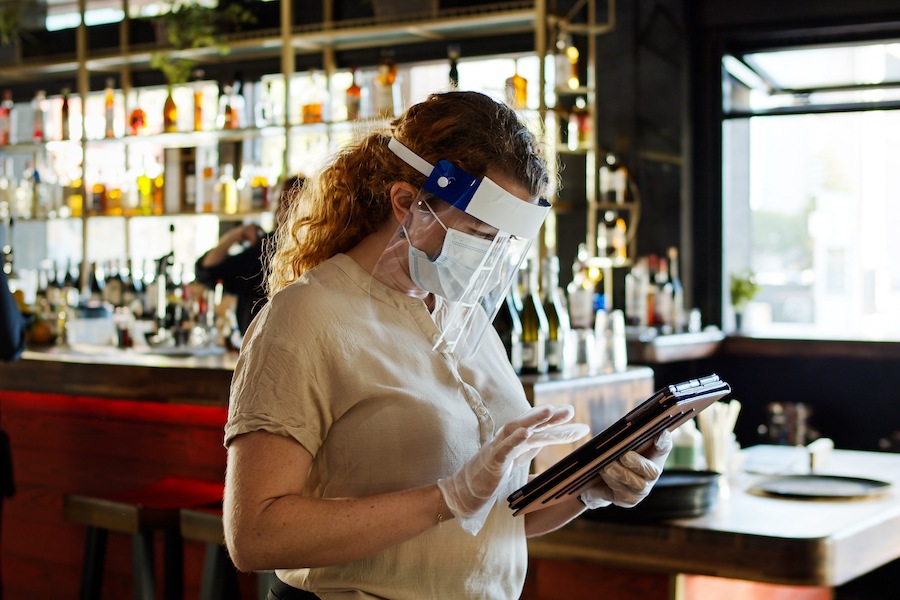 a server wearing a mask and face shield, as all servers are required to do when indoor dining returns to Philadelphia restaurants