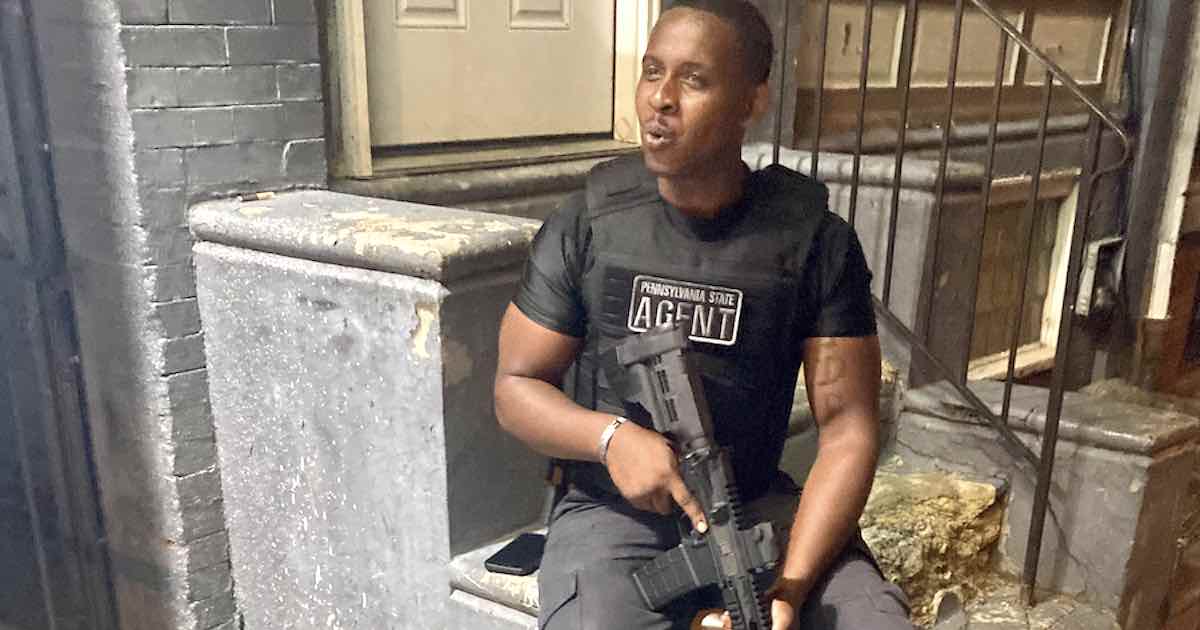 An armed security guard in front of Jim's West cheesesteak shop in West Philadelphia in 2023