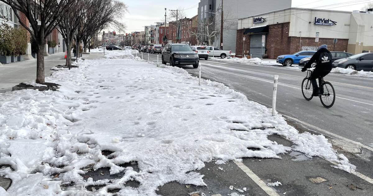 A bicyclists and an impassable bike lane at 11th and Washington, more than two weeks after a major storm brought lots of snow and ice to Philadelphia.